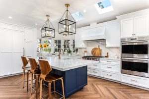 Kitchen with white cabinets and kitchen range hood to match, island has deep blue cabinets. 