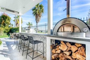 Outdoor kitchen with seating area, barbeque, and pizza oven
