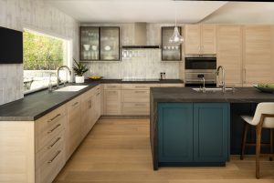 Beautiful kitchen remodel with moody blue cabinets on the large island and a modern, sleek kitchen hood. 